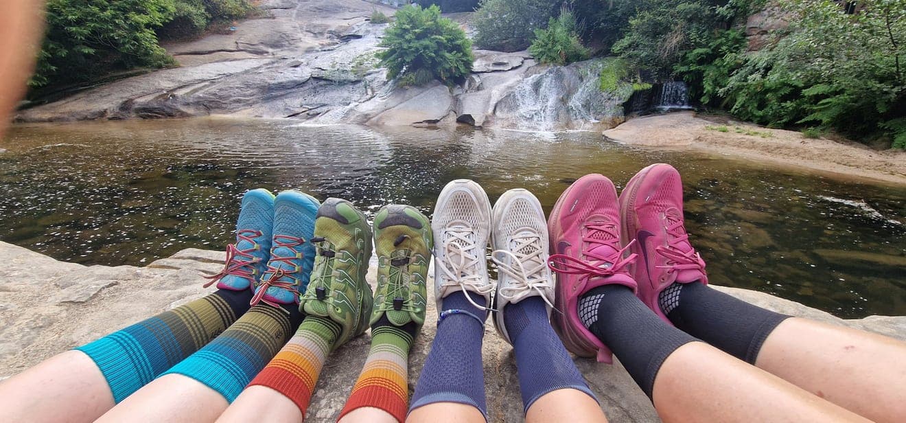 Quattro paia di scarpe durante una pausa davanti a una cascata.